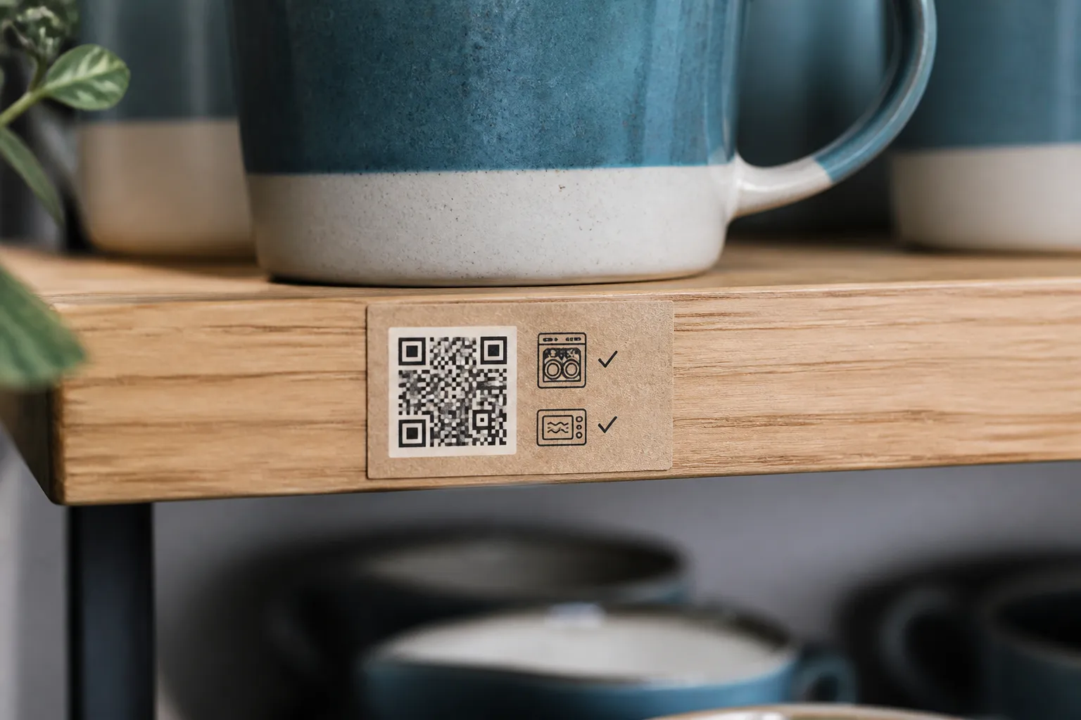 A close-up of a pottery shelf label where a small QR code sits beside two printed care rules.